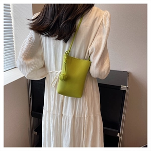 Detail of lime green mini bag featuring litchi texture and unique knot ball strap design