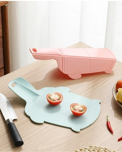 Pink multi-functional vegetable cutter set with a blue foldable cutting board on wood desk