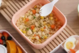 Detail of double-layer bento box with rice and vegetables plus reusable white spoon