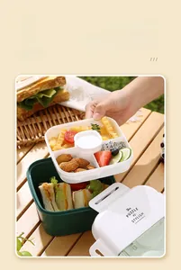 Detail of double-layer bento box with 4 compartments and round sauce container inside