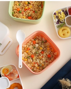 Flat lay of pink and green stackable bento lunch boxes with dividers and spork utensil