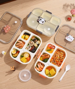 Detail of five-compartment lunch box with cartoon animal lid and spoon on wooden desk