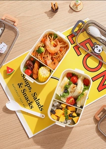 Detail of multi-compartment bear lunch box with handle and spoon on table