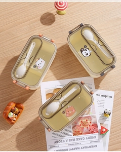 Top view of cartoon bear bento box with transparent lid and matching cutlery on wooden desk