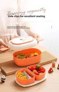 Detail of dual-layer orange lunch box with secure side buckles and cartoon bear lid