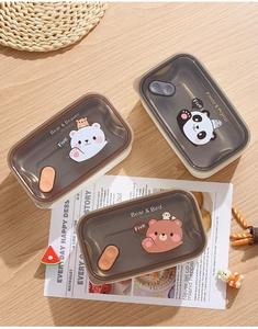 Detail of three SUS304 stainless steel lunch boxes with bear and panda lids on wood desk