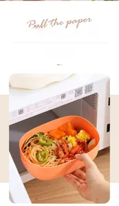 Orange plastic lunch box with pasta being placed into a microwave oven for heating