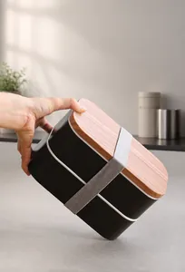 Detail of double-layer black lunch box with wood texture lid and elastic strap support