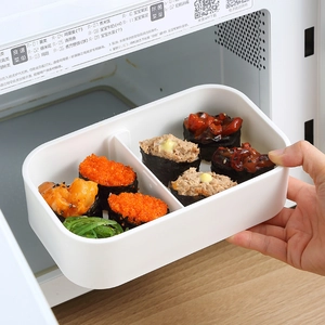 White double-layer plastic lunch box with dividers being placed in a microwave