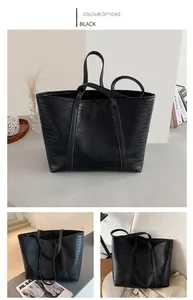 Detail of large black crocodile pattern tote bag with long straps and spacious interior
