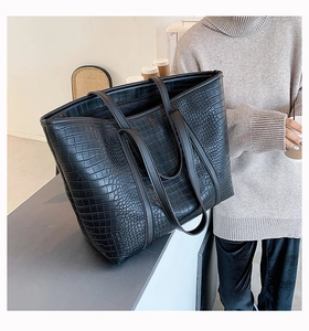 Macro detail of high-quality black faux leather tote bag with crocodile texture and stitching
