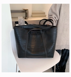 Detailed close-up of black crocodile-embossed faux leather on a large tote bag