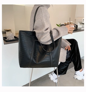 Detail of high-capacity black tote bag with premium crocodile pattern texture and handle