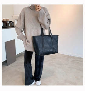 Detail of black crocodile texture leather tote bag with elegant long shoulder straps