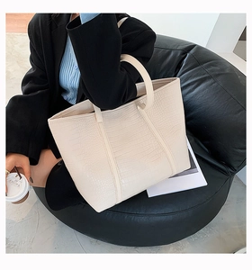 Detail of minimalist cream tote bag with elegant crocodile embossed faux leather texture