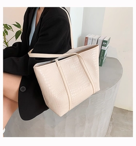 Close-up of a cream croco-effect tote bag with matte PU leather and shoulder strap