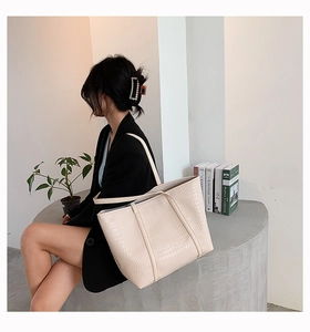 Close-up of beige tote bag with crocodile pattern and elegant leather texture detail