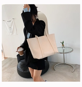 Detailed view of large cream tote bag with crocodile texture and elegant top handles