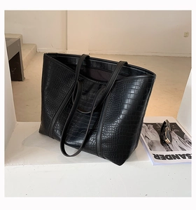 Detail shot of a black crocodile pattern tote bag in a minimalist architectural space