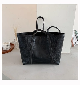 Close-up of black crocodile embossed tote bag with elegant handles and leather texture