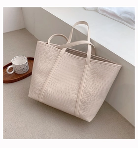 Close-up of cream white croco embossed tote bag featuring elegant textures and long handles