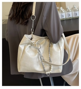Détail du sac seau crème montrant la texture géométrique, la chaîne et les perles
