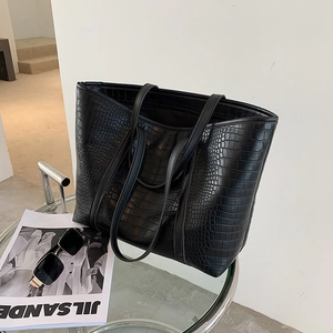 Detail of black crocodile texture large tote bag with sunglasses on a glass table
