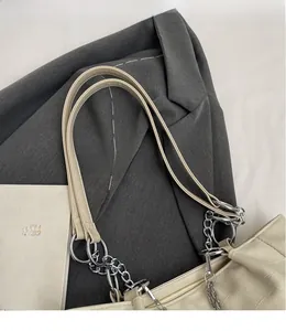 Détail du sac seau blanc crème avec motifs matelassés et bandoulière en chaîne argentée
