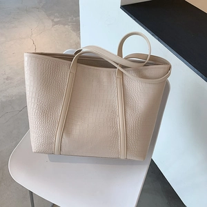 Detail of beige crocodile embossed texture on a large capacity leather tote bag