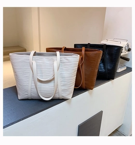 Detailed macro of large crocodile pattern tote bags in beige, brown and black leather