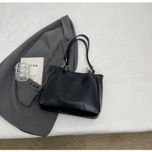 Vue détaillée du sac cabas en cuir noir mat avec anneaux argentés sur tissu blanc