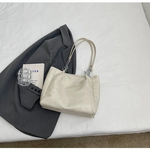 Gros plan sur un sac ivoire avec texture similicuir et bandoulière en chaîne argentée