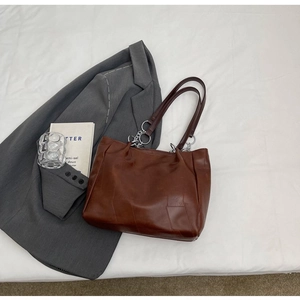 Détail du sac fourre-tout marron avec anneaux métalliques argentés et chaînettes