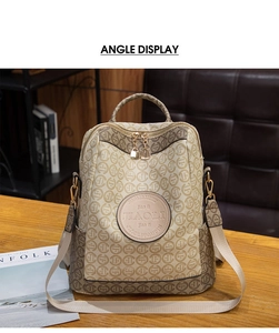 Detail view of khaki logo print backpack with golden zippers on a dark leather sofa