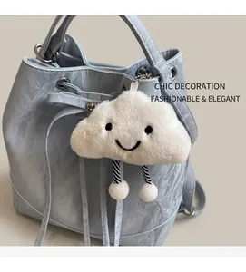 Close-up of white plush cloud charm with a smiling face on a mint blue bucket bag