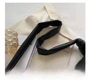 Close-up of black quilted croissant bag with soft leather handle and metal zipper detail