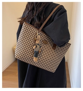 Detail of large houndstooth tote bag with brown leather handles and cute rabbit charm