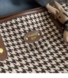 Detail of houndstooth tote bag featuring leather logo patch and cute rabbit pendant