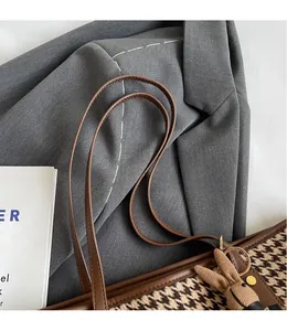 Close-up of houndstooth tote bag with brown leather handles and a cute bunny charm