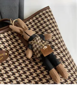 Detail of knitted rabbit bag charm on houndstooth tote with golden metal ring