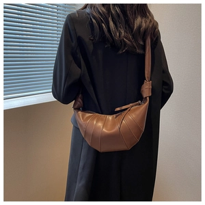 Detail of a dark brown croissant bag with quilted design and knotted strap on a model