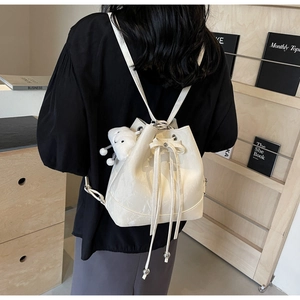 Rear view of model wearing a white marble-textured bucket backpack with plush bear charm