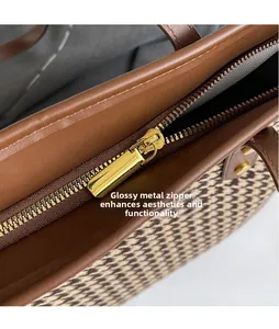 Close-up of golden smooth hardware zipper puller on houndstooth tote with leather trim