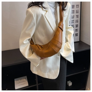 Detail showing the brown croissant bag leather texture and knotted strap design