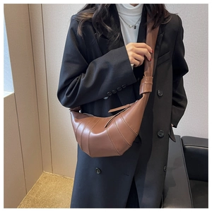 Detail of brown leather croissant bag with pleated stitching and knotted shoulder strap