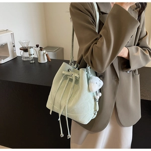 Detail of mint green bucket bag with drawstring closure and cute cloud pendant