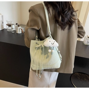 Detail of mint green bucket bag with leather texture and cute cloud plush charm accessory