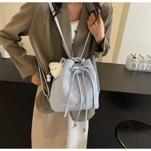 Detail of light blue bucket bag featuring soft pleated texture and cute white bear charm