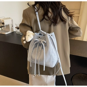 Detail view of mint green bucket bag featuring a decorative bow and plush sheep charm
