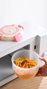 Clear round microwaveable lunch box containing pasta heating inside a microwave